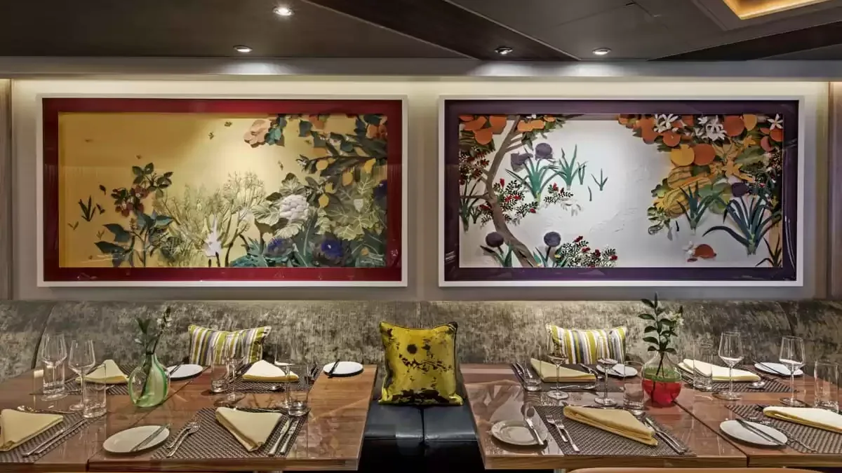 Tables dressées d’un restaurant du Seabourn Ovation devant deux panneaux peints de fleurs