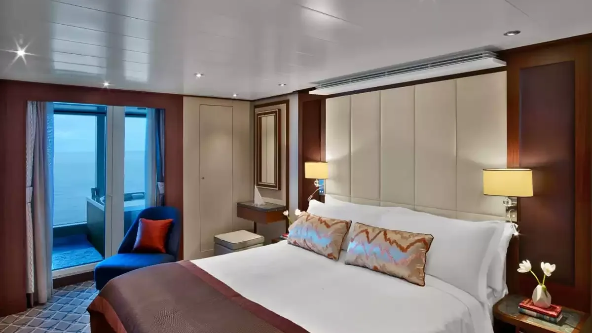 Chambre d’une suite du Seabourn Ovation, lit double et porte-fenêtre sur le balcon