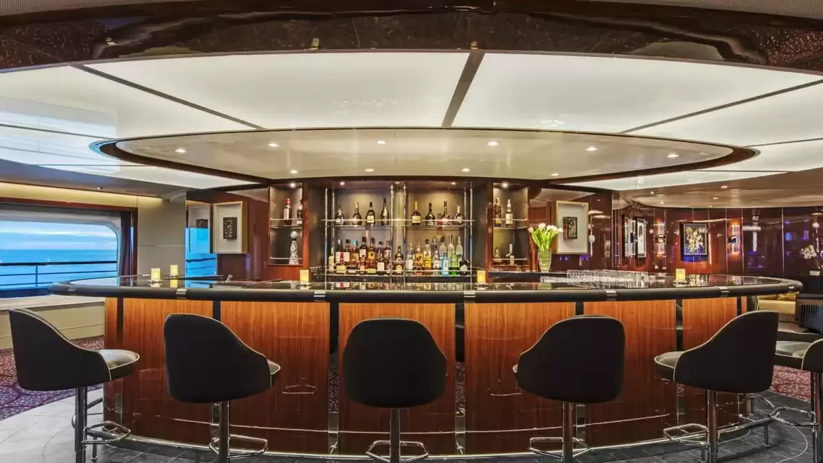 Bar en bois verni du Seabourn Ovation avec ses tabourets, la mer derrière les baies