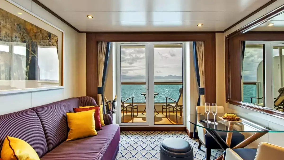 Salon d’une suite du Seabourn Ovation, canapé prune, coin repas et balcon