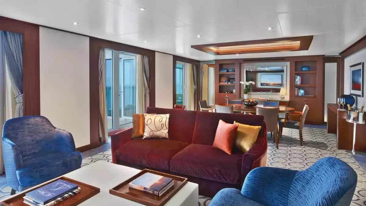 Salon d’une suite du Seabourn Ovation, canapé bordeaux et fauteuils bleus