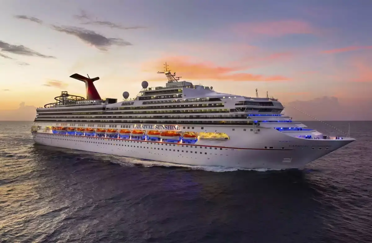 Le Carnival Sunshine naviguant au coucher du soleil avec sa cheminée ailée emblématique
